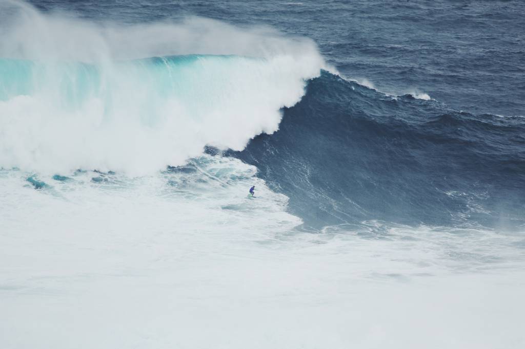 robert-bye-qdGZ6IrJCP8-unsplash Um homem surfando uma onda gigante a quebrar sobre ele ,a Nazaré, em Portugal