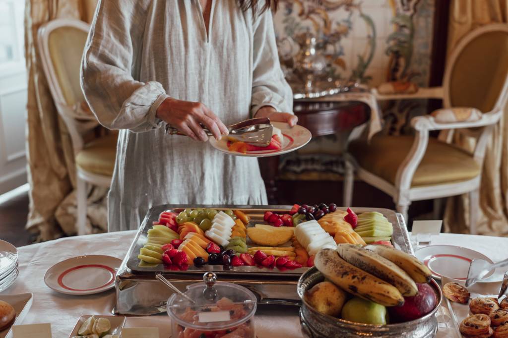 Mesa de café da manhã, com detalhe para uma bandeja de frutas fatiadas