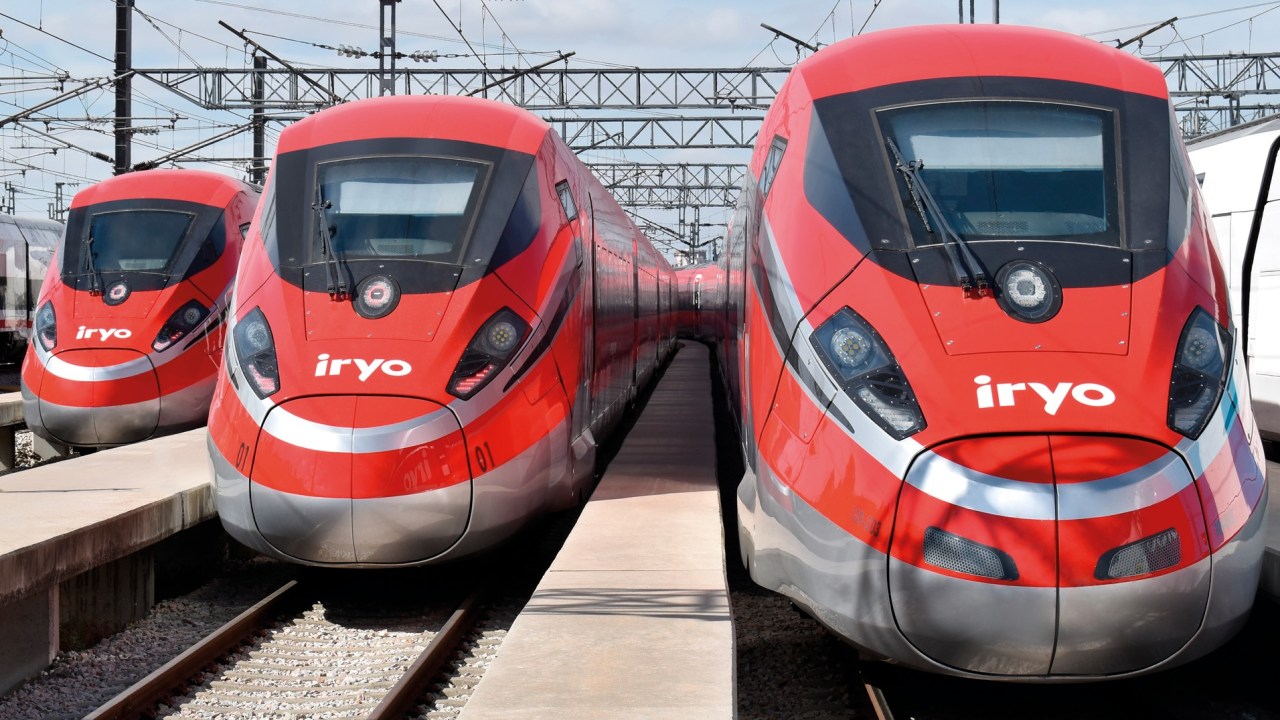 A fotografia colorida mostra dois trens vermelhos de frente