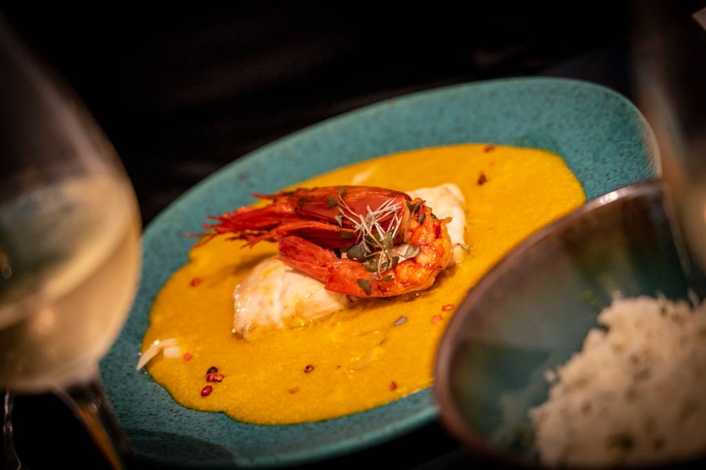 9 Prato do restaurante com um creme amarelo na base, um filé de peixe e um grande camarão ao centro