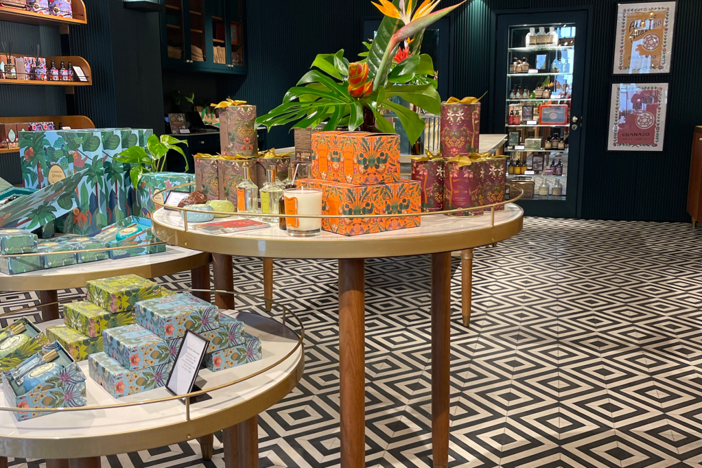 Detalhe de uma mesa da loja da Granado em Portugal, com piso quadriculado e uma mesa redonda com perfumes em cima