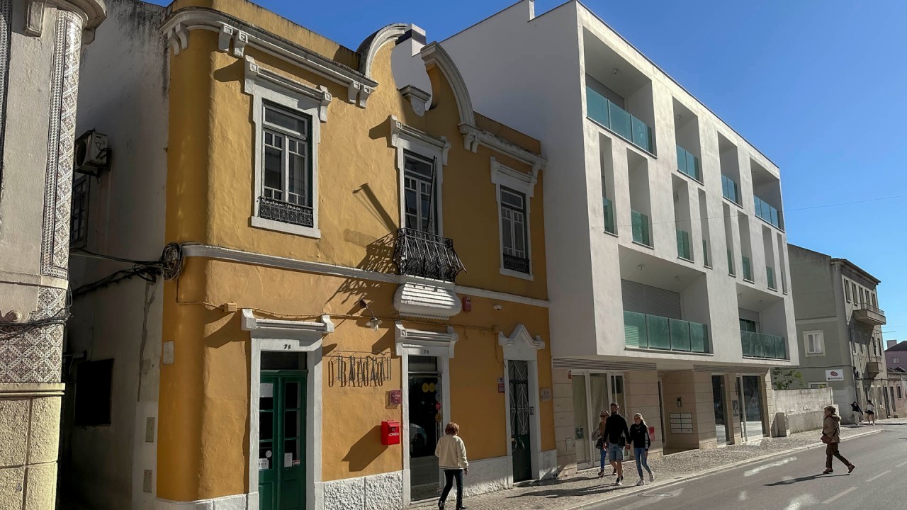 Uma casa amarela de dois andares com janelas verdes, onde funciona o restaurante Ó Balcão