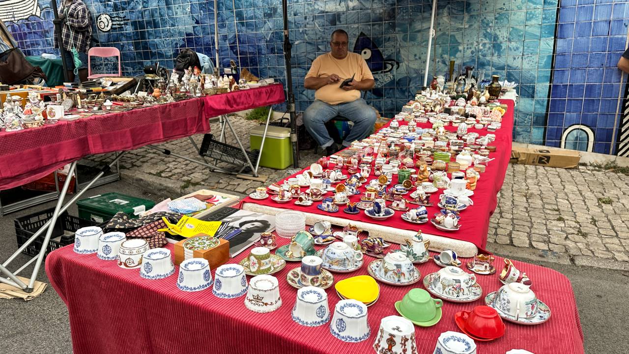 barraca de xícaras e louças com um vendedor ao fund, na Feira da Ladra