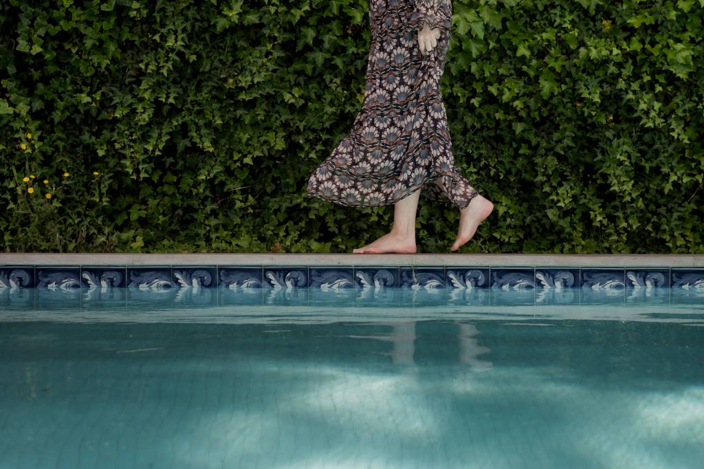 2024_Nuvem-203 A imagem mostra detalhe da piscina do hotel com os pés de uma mulher caminhando na beirada