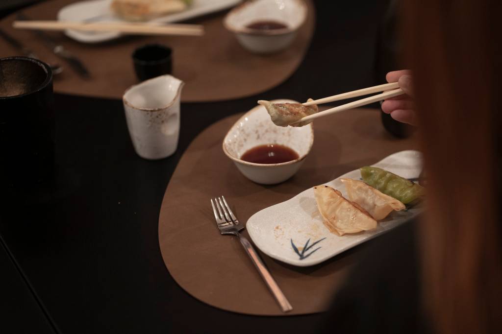 Prato de gyozas servidos na mesa do restaurante Spices, com uma pessoa a comê-los com chopsticks