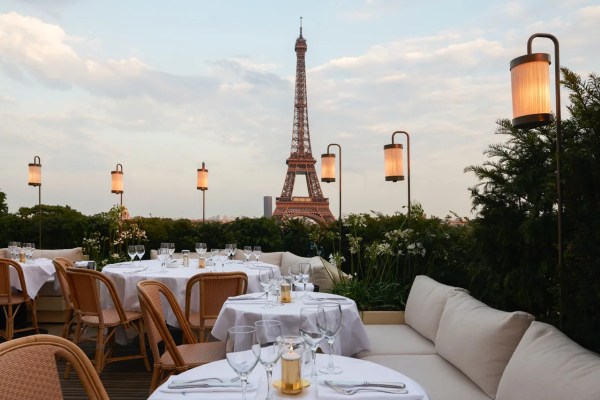 Terraço com mesas e cadeiras, com vista para a Torre Eiffel